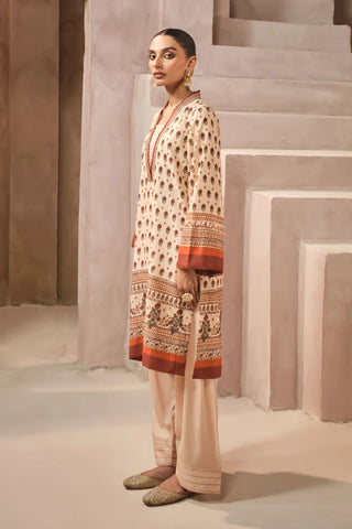 Woman wearing a patterned kurta with shalwar pants in a neutral setting
