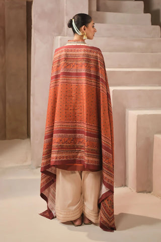 Woman wearing a patterned shawl with Urdu calligraphy standing on a staircase