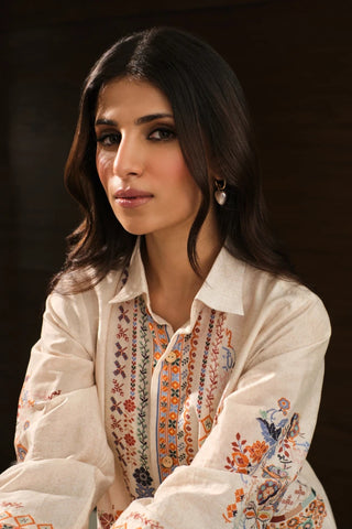 Woman wearing a white embroidered blouse with a dark background