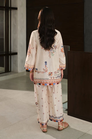 Woman wearing a cream-colored embroidered outfit in an indoor setting