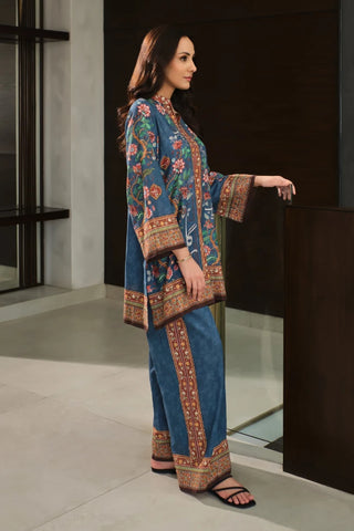 Woman wearing a blue and patterned outfit standing indoors.