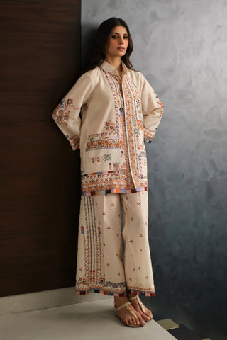 Woman wearing a traditional outfit with intricate patterns against a textured wall.